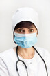 Face of a female doctor in a medical mask cap with brown eyes, close-up.