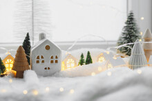 Atmospheric Miniature Winter Village. Stylish Cute Little Ceramic Houses And Christmas Wooden Trees On Soft Snow Blanket With Glowing Lights. Christmas Modern White Background. Happy Holidays!