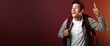 © MADMAT - Excited College Student with Backpack on a Maroon Background with Space for Copy.