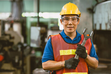 Wall Mural - Portrait Asian technician engineer male hand holding giant wrench happy smile. heavy industry employee enjoy working.good labor welfare