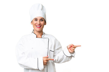 Wall Mural - Middle-aged chef woman over isolated background surprised and pointing side