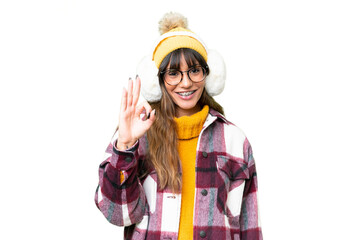 Canvas Print - Young caucasian woman wearing winter muffs over isolated chroma key background showing ok sign with fingers