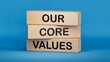 Our core values symbol. Concept words 'Our core values' on wooden blocks, businessman hand. Business and our core values concept. Copy space.3D rendering on blue background.

