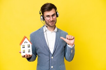 Canvas Print - Young caucasian man holding a house isolated on white background proud and self-satisfied