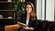 © Studio Nova - Happy professional female psychologist holding clipboard sitting at sofa in her office