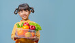 A little girl is holding a bowl of fruits and vegetables.