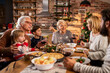 © Geber86 - Multigenerational caucasian family having a christmas and new year dinner at home with a christmas tree in the background