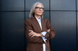© Ivan Traimak - confident well-groomed old lady with gray hair in glasses is dressed in a brown jacket and shirt spends lunchtime walking along the street