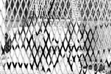 A steel security fence in a black and white film negative.