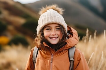 Portrait of a smiling little girl in winter jacket and hat outdoors