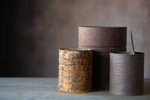 Three Rusty Cans With Brown Background