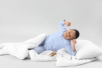 Wall Mural - Little African-American boy with soft blanket lying on light background