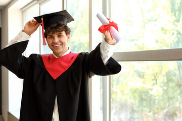 Poster - Male graduate student with diploma near window in room