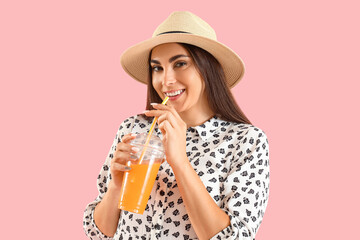 Wall Mural - Young woman drinking juice on pink background