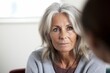 © Anne Schaum - Portrait of senior woman looking at camera while talking to psychotherapist