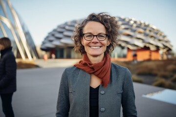 Wall Mural - Portrait of smiling woman with eyeglasses in front of modern building