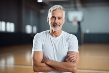 Portrait of confident senior man standing with arms crossed in basketball court