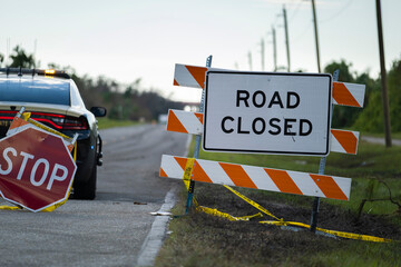 Wall Mural - Police patrol car at yellow protective barrier at street construction site. Warning road sign about utility work