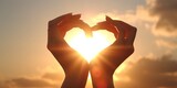 Female hands in the form of heart against the sky pass sun beams. Hands in shape of love heart