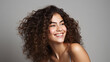 © Nico Vincentini - Portrait of a woman highlighting skincare and beauty cosmetics for a radiant, healthy glow, set against a modern studio background. Cheerful model with beautiful curly hair smiling. Generative AI