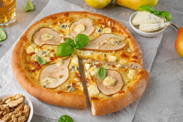 Wall Mural - Delicious pizza with pears, gorgonzola cheese, walnuts and basil on a gray concrete background.