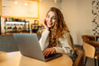 © maxbelchenko - Young freelancer woman sitting in a cafe at a laptop working online. The concept of education, freelancing.