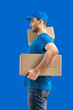 Delivery man with a box. Courier in uniform cap and t-shirt service fast delivering orders. Young guy holding a cardboard package. Character on isolated background for mockup design