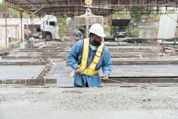 Wall Mural - Construction worker uses long steel trowel spreading wet concrete pouring at precast concrete wall construction site. Worker or mason working or making smooth surface of concrete with equipment tool