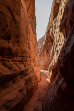 Hike in the narrow Kaolin Wash slot canyon along White Domes Hiking Trail in Valley of Fire State Park in Mojave desert, Nevada, USA. Massive rugged cliffs of striated red and white rock formations
