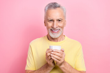 Poster - Photo of positive man with gray beard dressed yellow t-shirt hands hold cup of coffee in morning isolated on pink color background