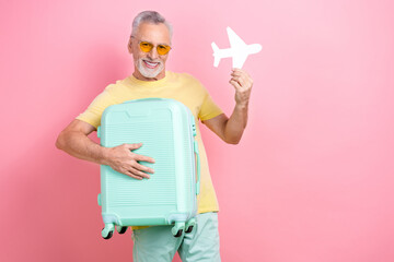 Sticker - Photo of satisfied optimistic man with beard dressed yellow t-shirt holding small paper plane valise isolated on pink color background