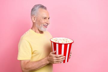 Sticker - Photo of senior grey hair old man eating tasty bucket crisps looking curious empty space new marvel film isolated on pink color background