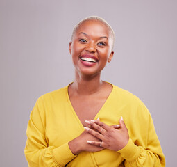 Poster - Grateful, smile and portrait of a black woman in a studio with sweet, happy and positive attitude. Empathy, gratitude and young African female model with thank you gesture isolated by gray background