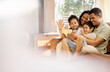© Talia Mdlungu/peopleimages.com - Tablet, video call and family with wave, love and smile on a living room sofa at home. Mother, dad and children together with online communication of parents and kids with discussion and mockup space