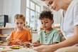 © LIGHTFIELD STUDIOS - interracial children playing with didactic montessori material near female teacher, diversity
