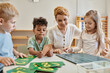 © LIGHTFIELD STUDIOS - happy interracial kids learning how to count near numbers and female teacher, Montessori school
