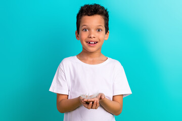 Poster - Portrait of adorable sweet schoolchild arms palms hold feather toothy smile good mood isolated on turquoise color background