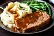 Enjoy a hearty, homemade meal with juicy slices of meatloaf smothered in savory gravy, served alongside creamy mashed potatoes and green beans