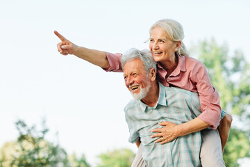 Wall Mural - woman man outdoor senior couple happy lifestyle retirement together smiling love fun elderly active vitality nature mature portrait piggyback game