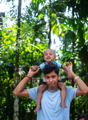 Wall Mural - South asian young man with his little baby boy in a outdoor park 