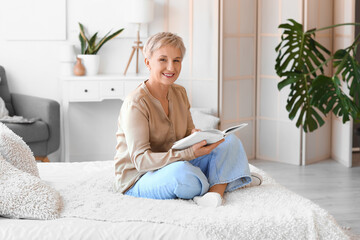 Wall Mural - Mature woman reading book in bedroom