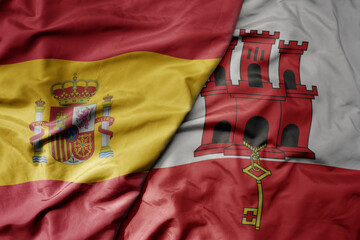 big waving national colorful flag of spain and national flag of gibraltar .