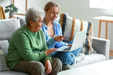Wall Mural - Young woman with her grandmother using laptop at home