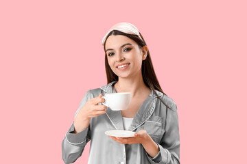 Sticker - Young woman in pajamas with cup of coffee on pink background