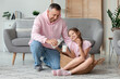 © Pixel-Shot - Little girl with her father sitting on floor and drinking milk in living room
