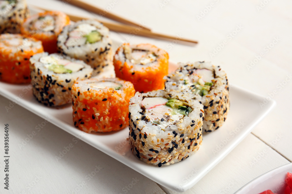 Plate with tasty sushi rolls on white wooden table, closeup