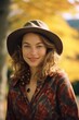 © Glittering Humanity - A beautiful young woman posing in nature, wearing a stylish hat, and smiling brightly captures the perfect autumn fashion portrait