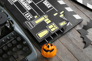 Typewriter with clapperboard and Halloween decor on brown wooden background