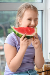 Sticker - Little girl eating fresh watermelon in kitchen