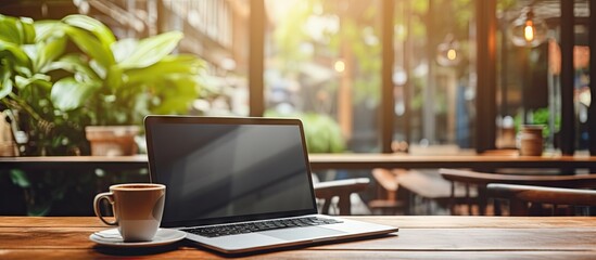 Poster - Coffee cup on wooden table in coffee shop with black blank screen workspace